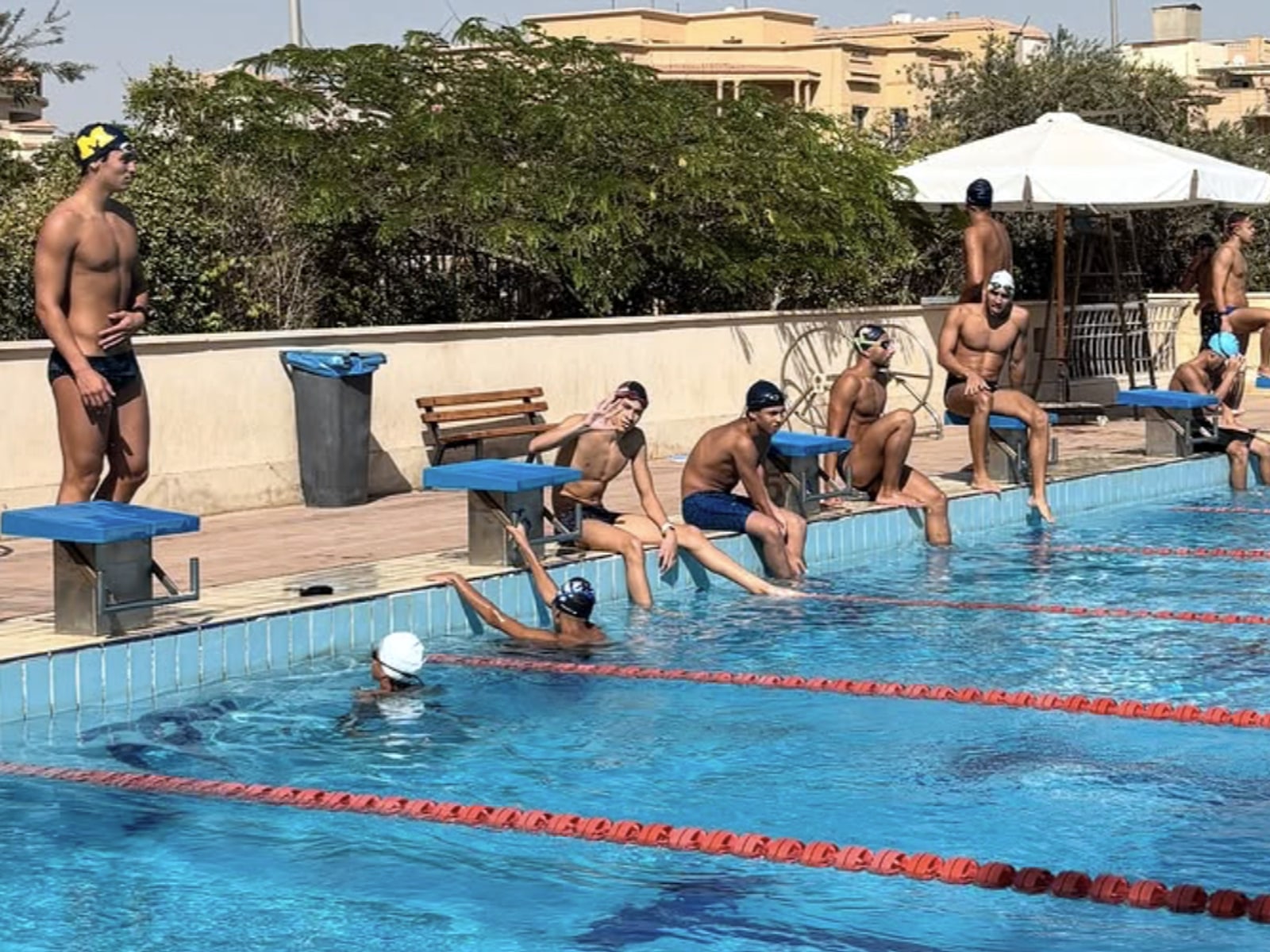 SWEEP swimmers waiting on the blocks between reps, one of them swimming the lane behind